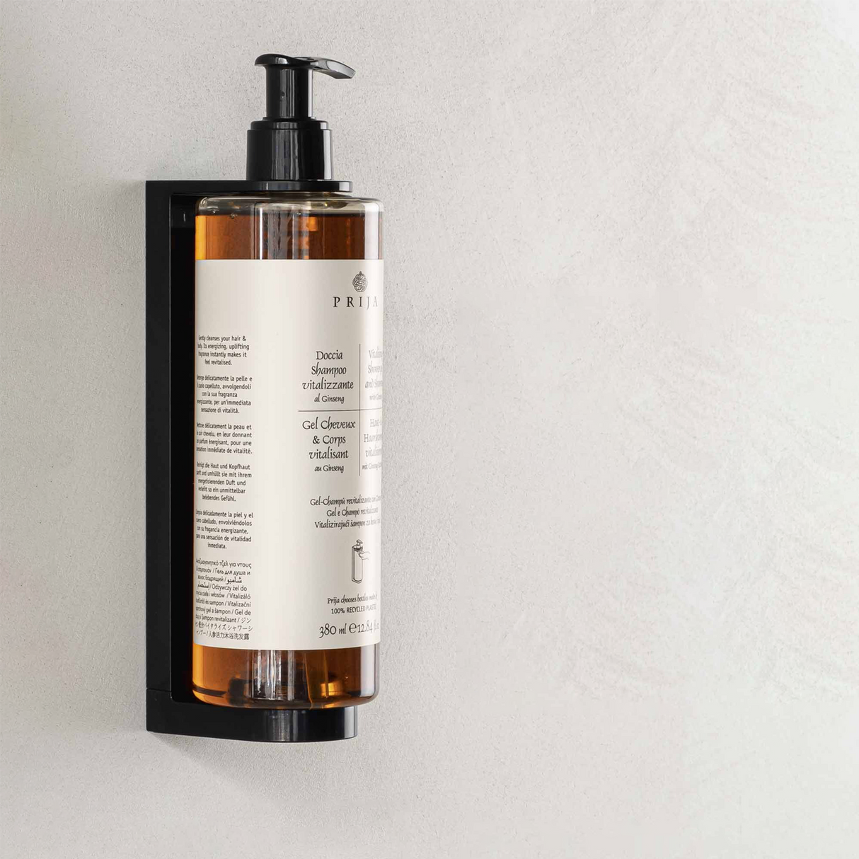 Flacon cu gel de duș și șampon din gama de cosmetice hoteliere Prija în suport de perete, pe perete